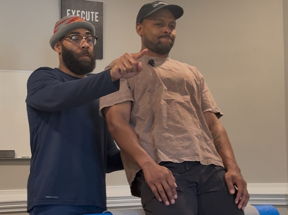 Eric Paige cueing a client's shoulder position during a movement assessment