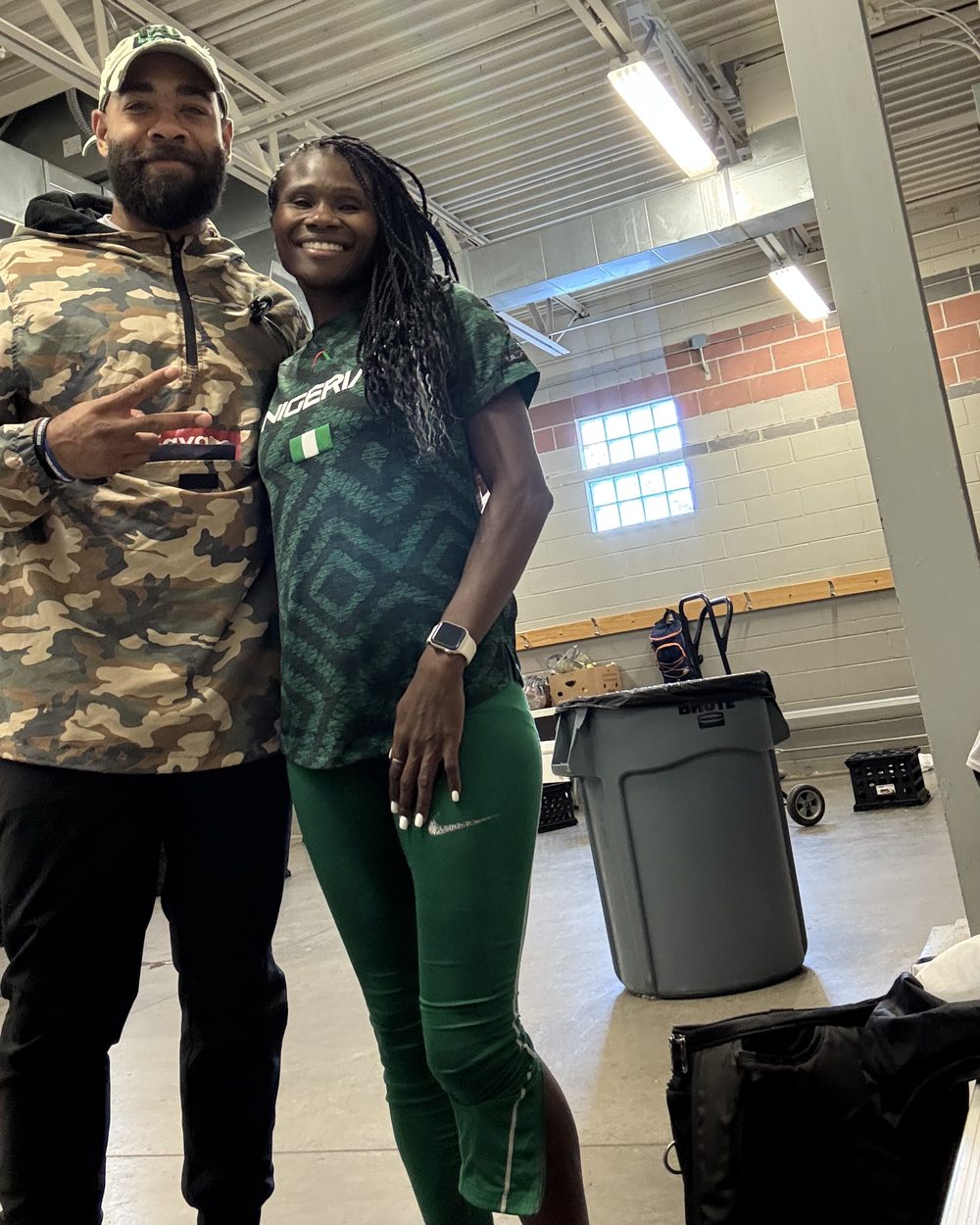 Eric Paige with a track athlete in Nigeria national team kit in the warm-up area at a meet