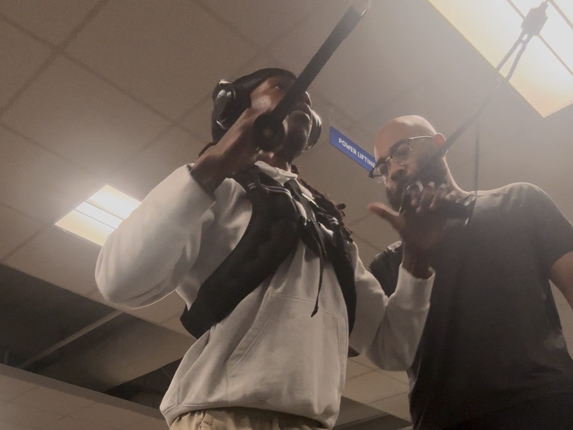 Eric Paige coaching a loaded split squat with an athlete in the weight room