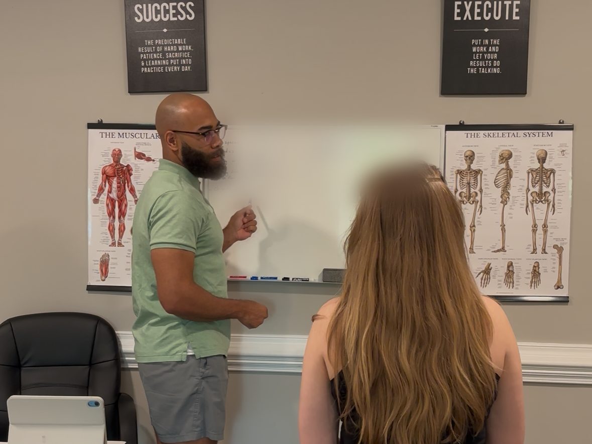 Eric Paige working through assessment findings at the whiteboard with a client