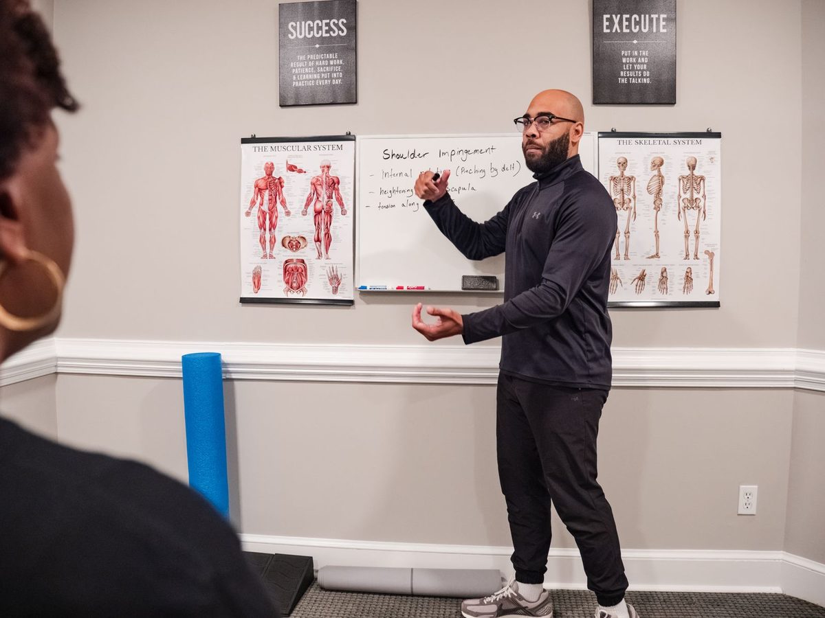 Eric Paige walking a client through shoulder mechanics at the whiteboard