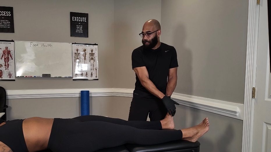 Eric Paige working through a client's lower limb on a treatment table in his Raleigh studio