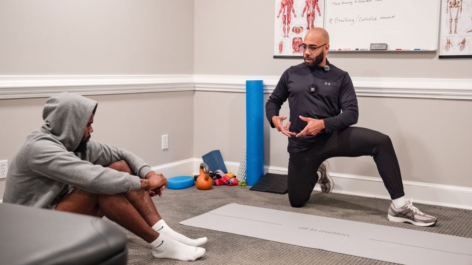 The EPF Wellness Consulting studio in Raleigh, with Eric Paige coaching a client beside anatomy charts, a whiteboard and mobility equipment
