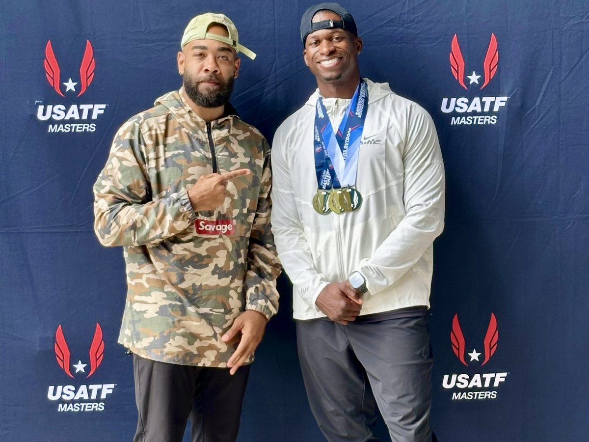 Eric Paige alongside a medalist athlete at a USATF Masters championship backdrop